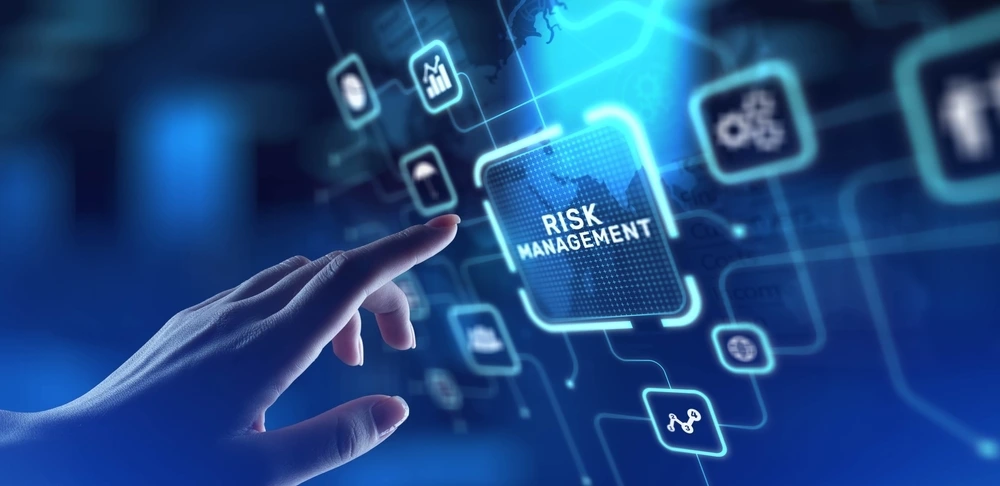 A hand points to a glowing blue digital button labeled "RISK MANAGEMENT" on a futuristic interface with various abstract icons in the background.